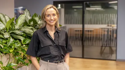 Lisa Duigan, Data Centres Sector Lead, Europe, inside plant based office standing in black shirt.